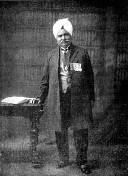 An old photograph of Sir Ganga Ram standing in a turban and long coat