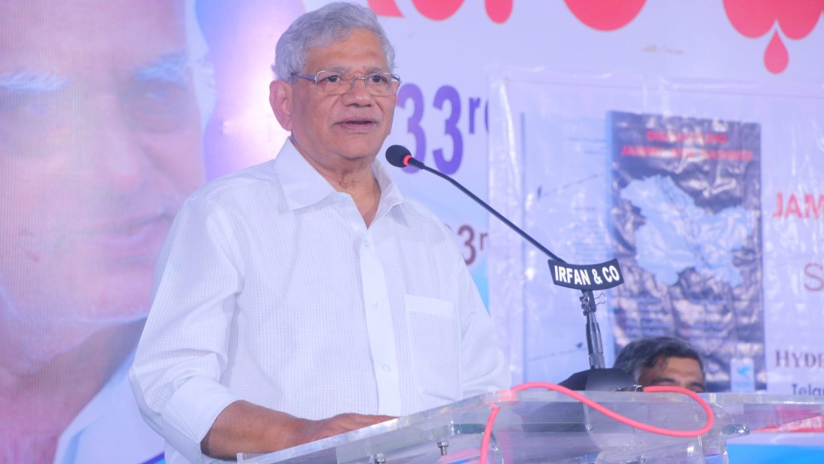 Sitaram Yechury with grey hair in a white kurta speaking at a lectern