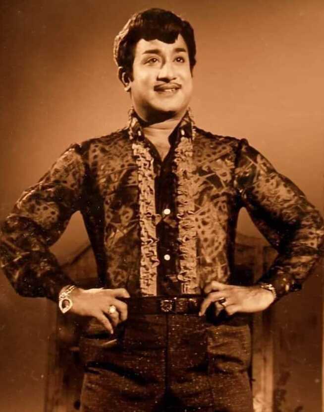 Sivaji Ganesan standing with his hands on his hips, in a patterned shirt