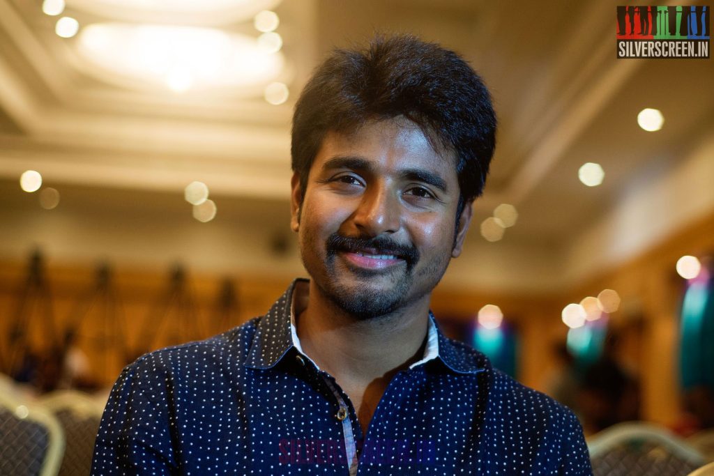 Sivakarthikeyan smiling in a dark printed shirt in a hotel hall