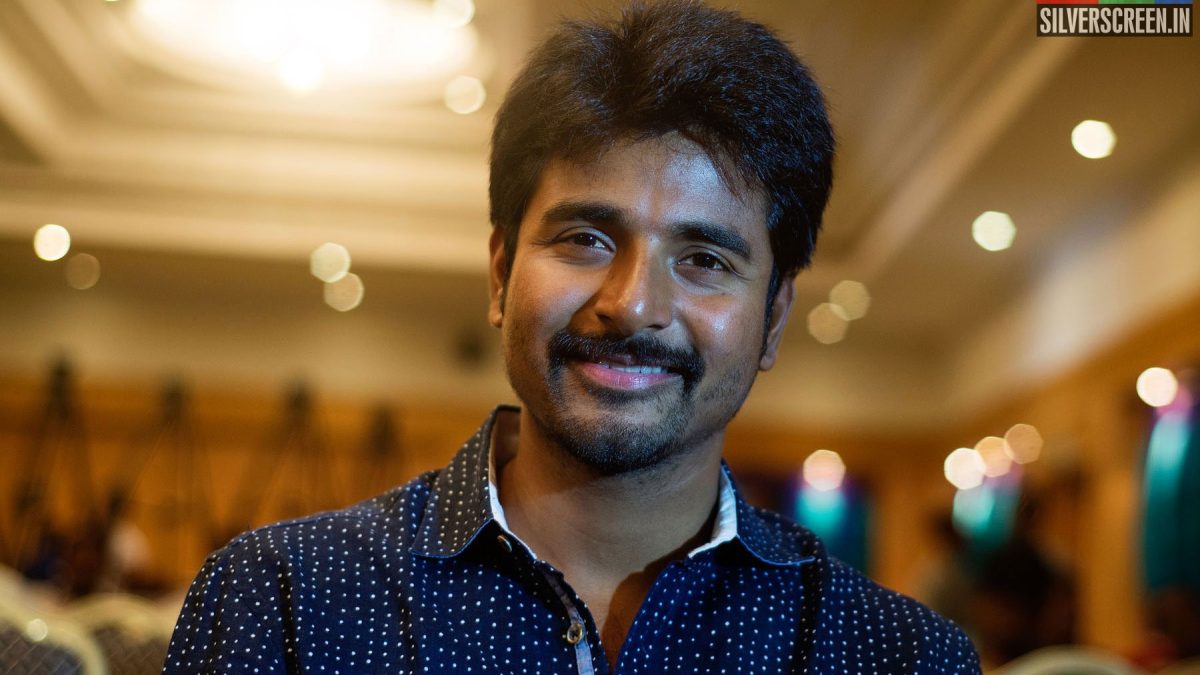 Sivakarthikeyan smiling in a dark printed shirt in a hotel hall