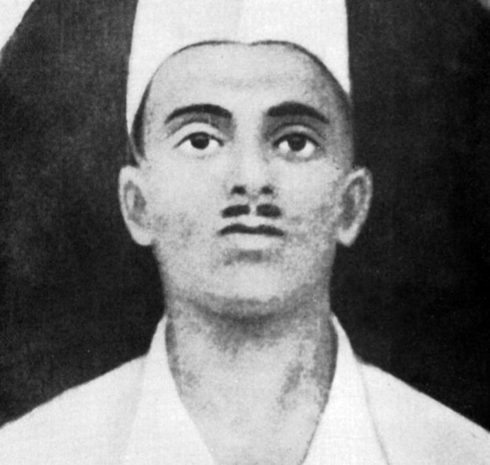 A black-and-white portrait of Sukhdev Thapar in a white cap