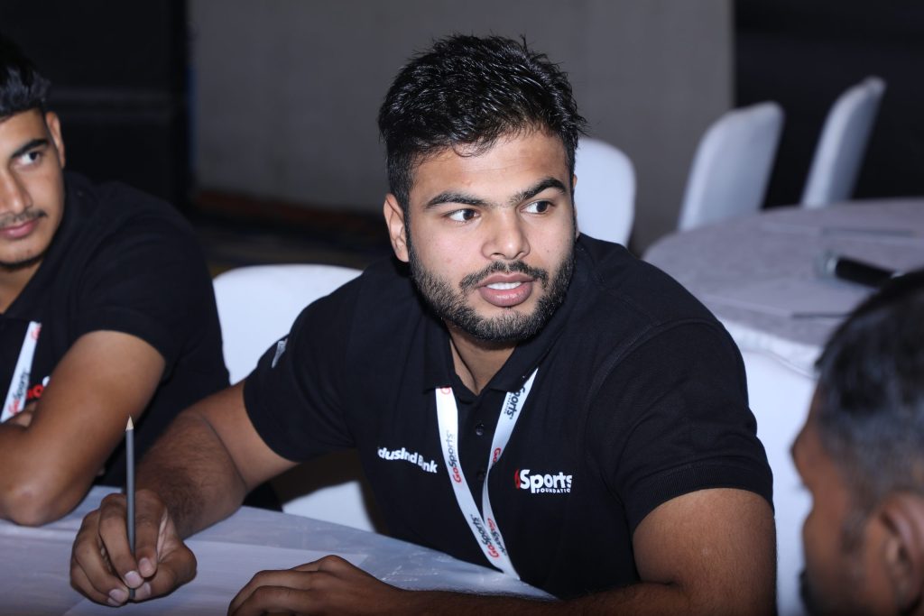 Sumit Antil in a black polo shirt seated at a table, looking to the side