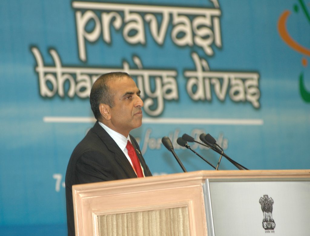 Sunil Mittal in a dark suit and red tie speaking at a lectern