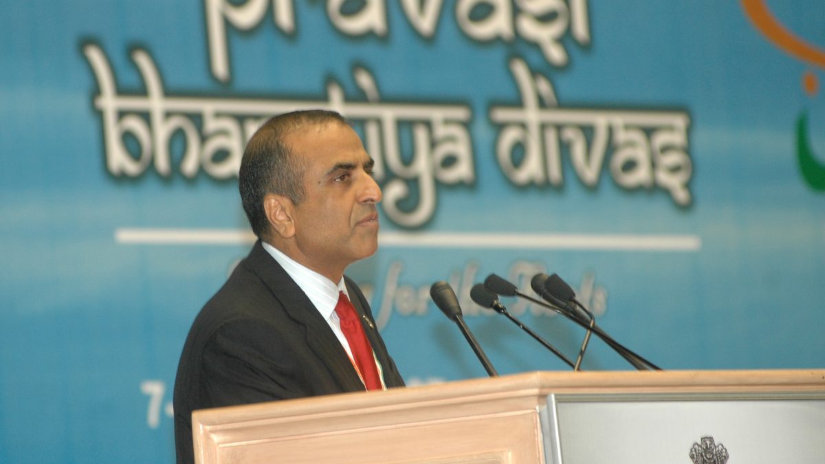 Sunil Mittal in a dark suit and red tie speaking at a lectern