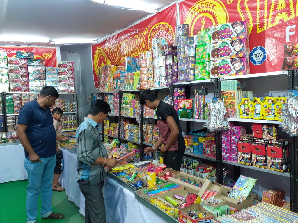 Shoppers browsing boxes of firecrackers at a stall