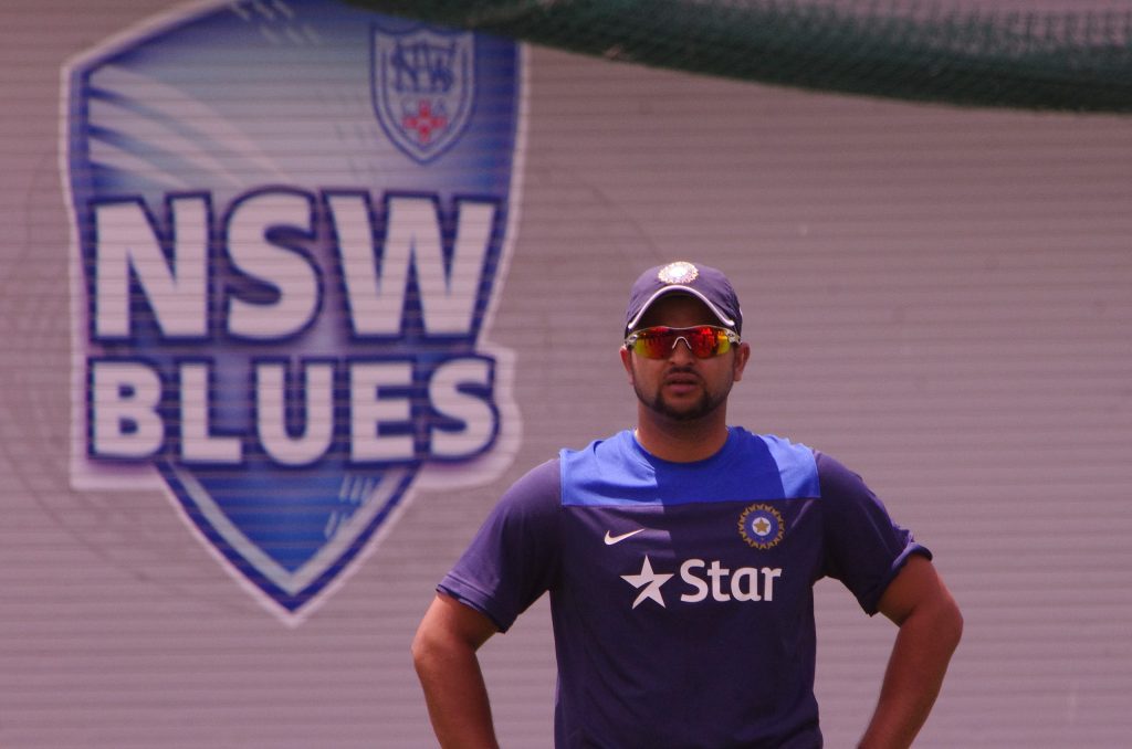 Suresh Raina in sunglasses and an India training shirt standing with his hands on his hips