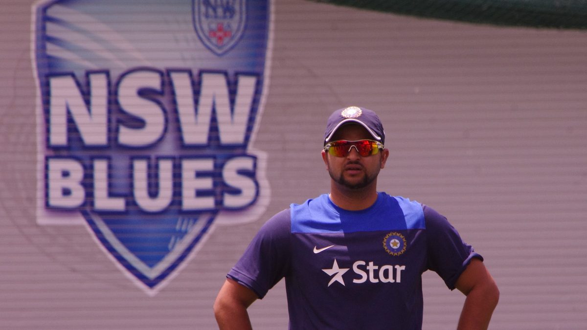 Suresh Raina in sunglasses and an India training shirt standing with his hands on his hips