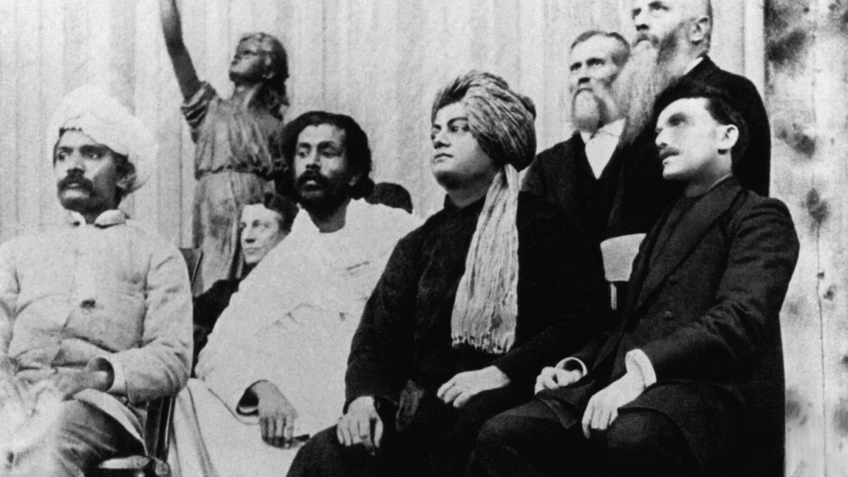 Swami Vivekananda in turban and robe seated on the platform at the Parliament of Religions in Chicago