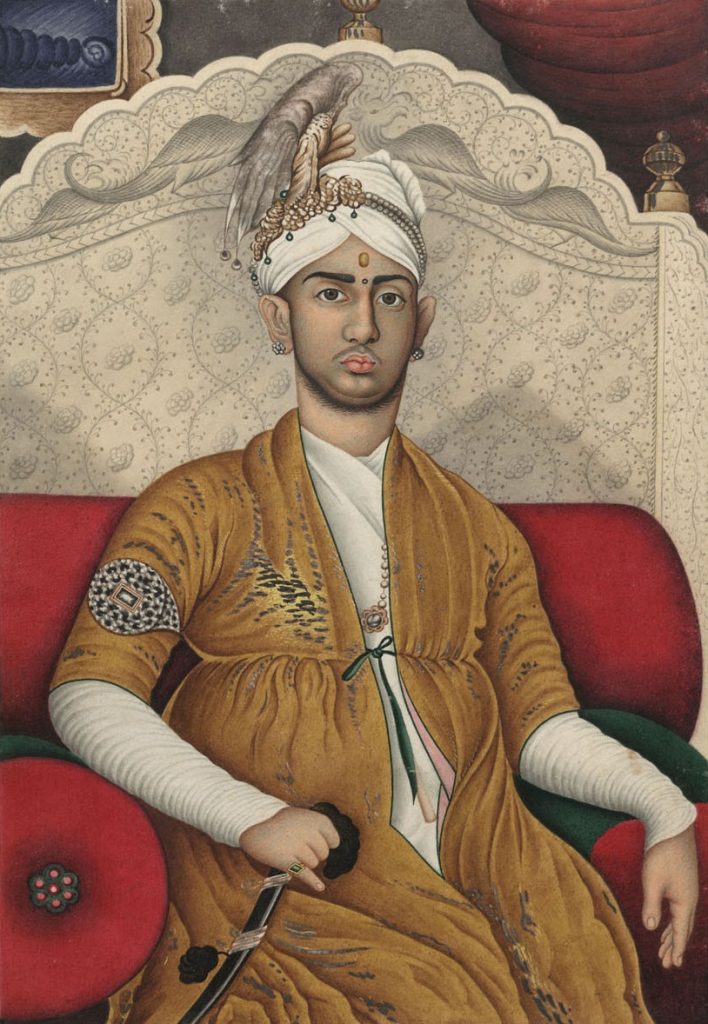 Painted portrait of Swathi Thirunal in a turban and yellow robe, seated against a red cushion