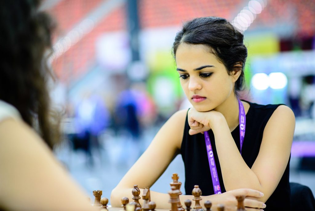 Tania Sachdev resting her chin on her hands, concentrating at a chessboard