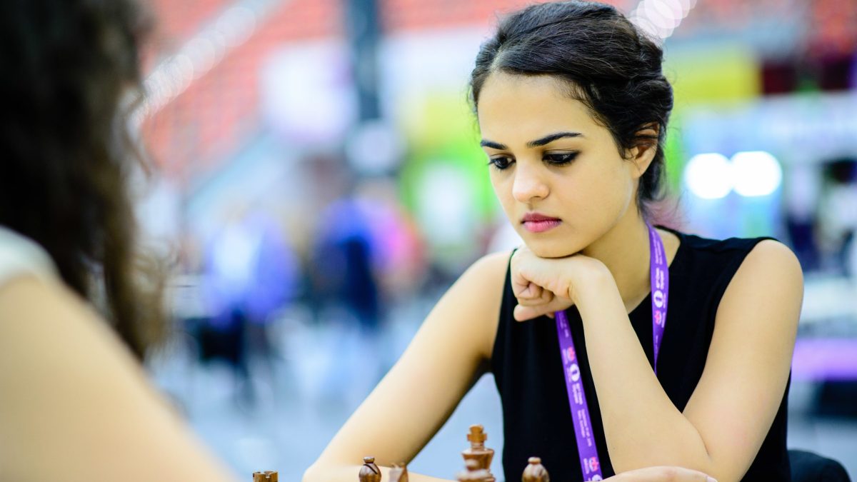 Tania Sachdev resting her chin on her hands, concentrating at a chessboard