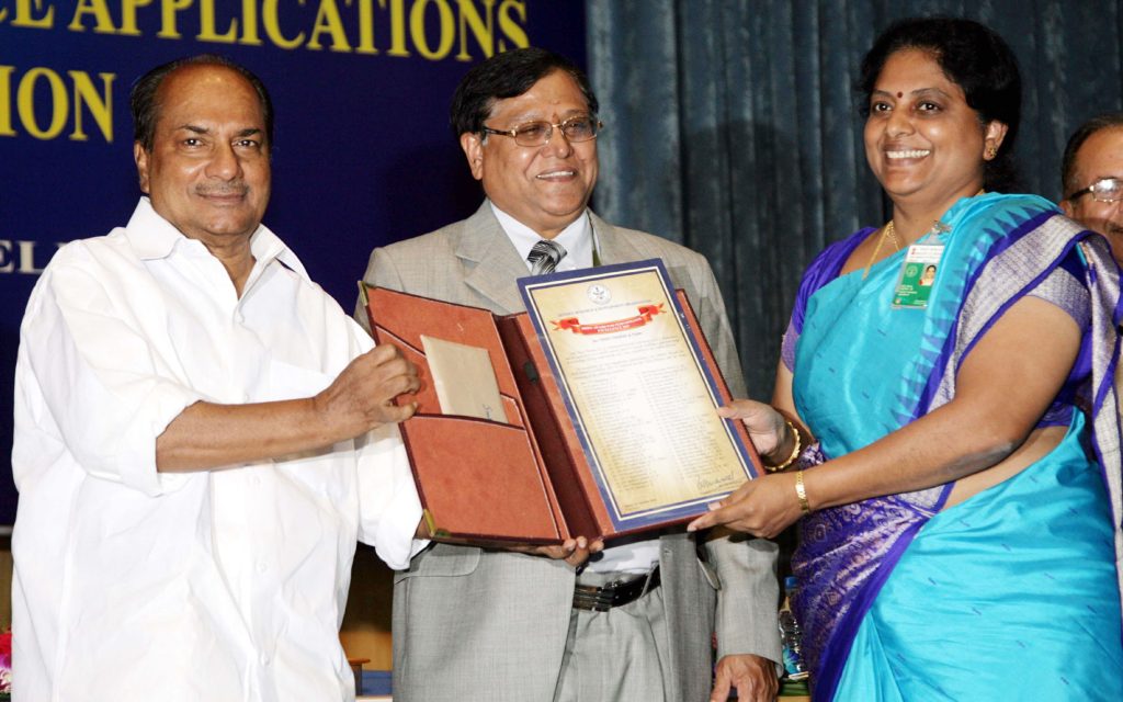 Tessy Thomas in a blue sari receiving an award certificate from Defence Minister A. K. Antony