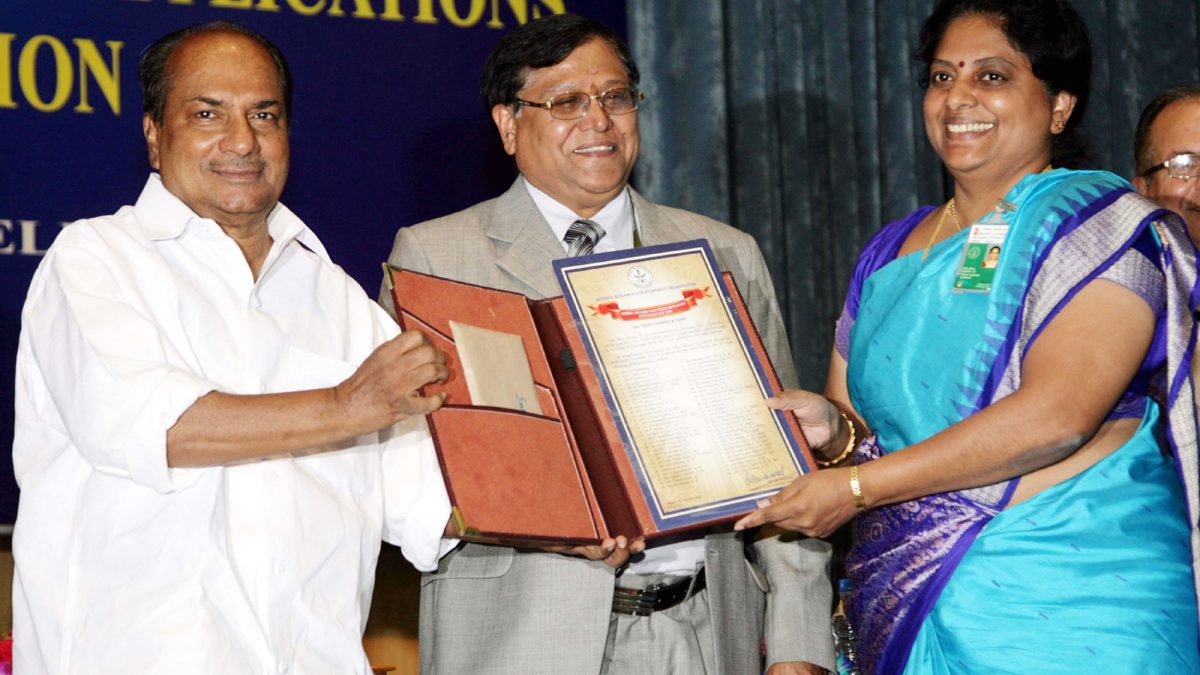 Tessy Thomas in a blue sari receiving an award certificate from Defence Minister A. K. Antony