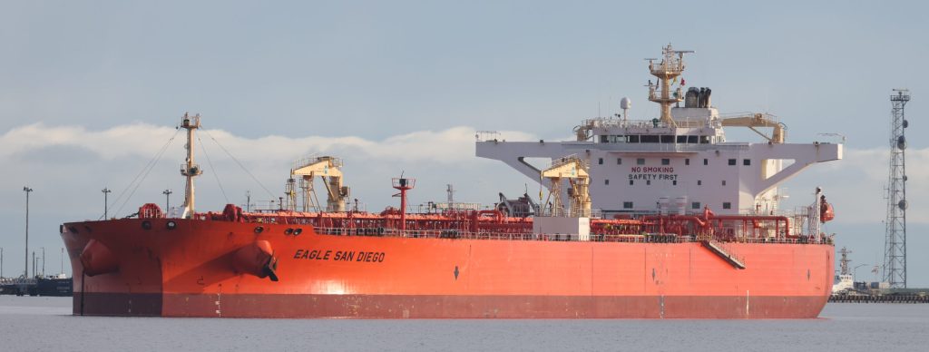 A red crude oil tanker moored in a harbour