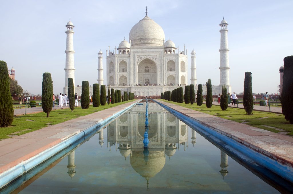 The white marble Taj Mahal and its reflection in the long water channel of its garden