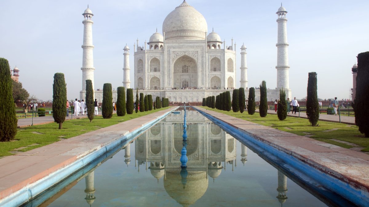 The white marble Taj Mahal and its reflection in the long water channel of its garden