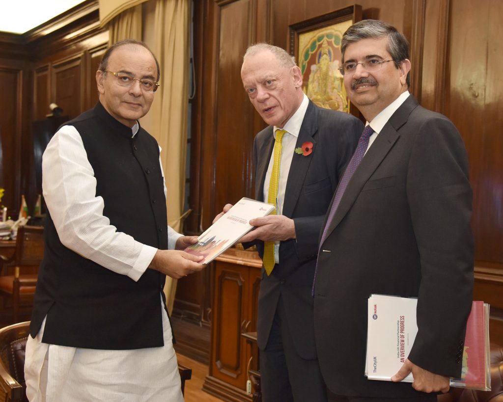 Uday Kotak in a dark suit standing with Arun Jaitley and Gerry Grimstone