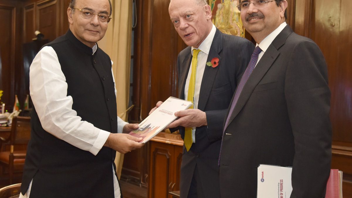 Uday Kotak in a dark suit standing with Arun Jaitley and Gerry Grimstone