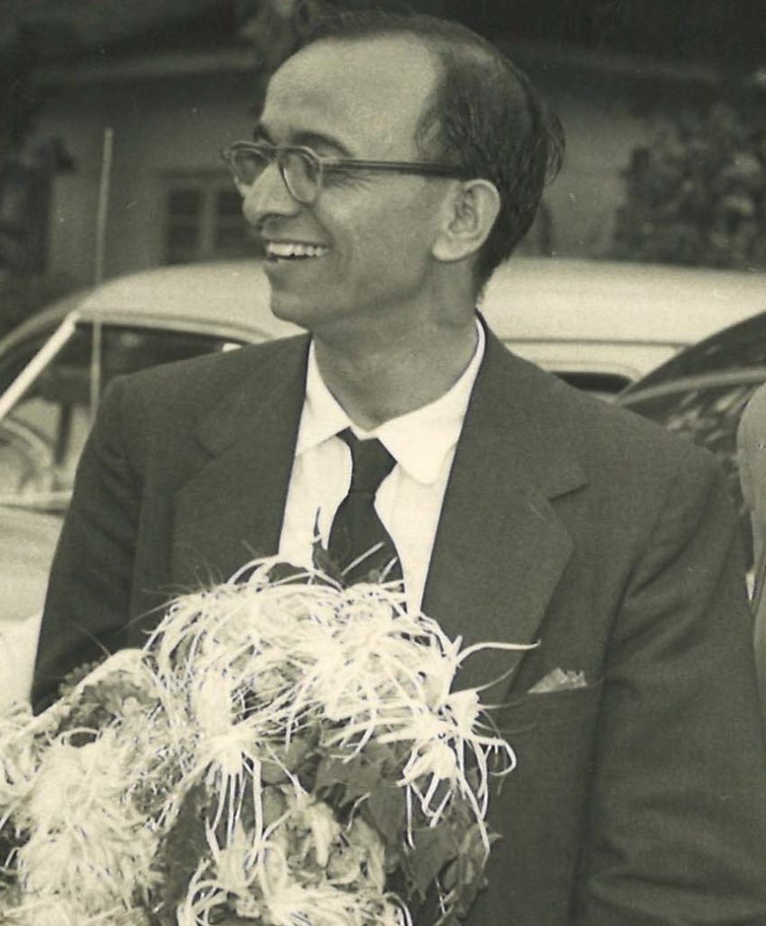A black-and-white photograph of Umashankar Joshi in glasses and a suit, holding a garland