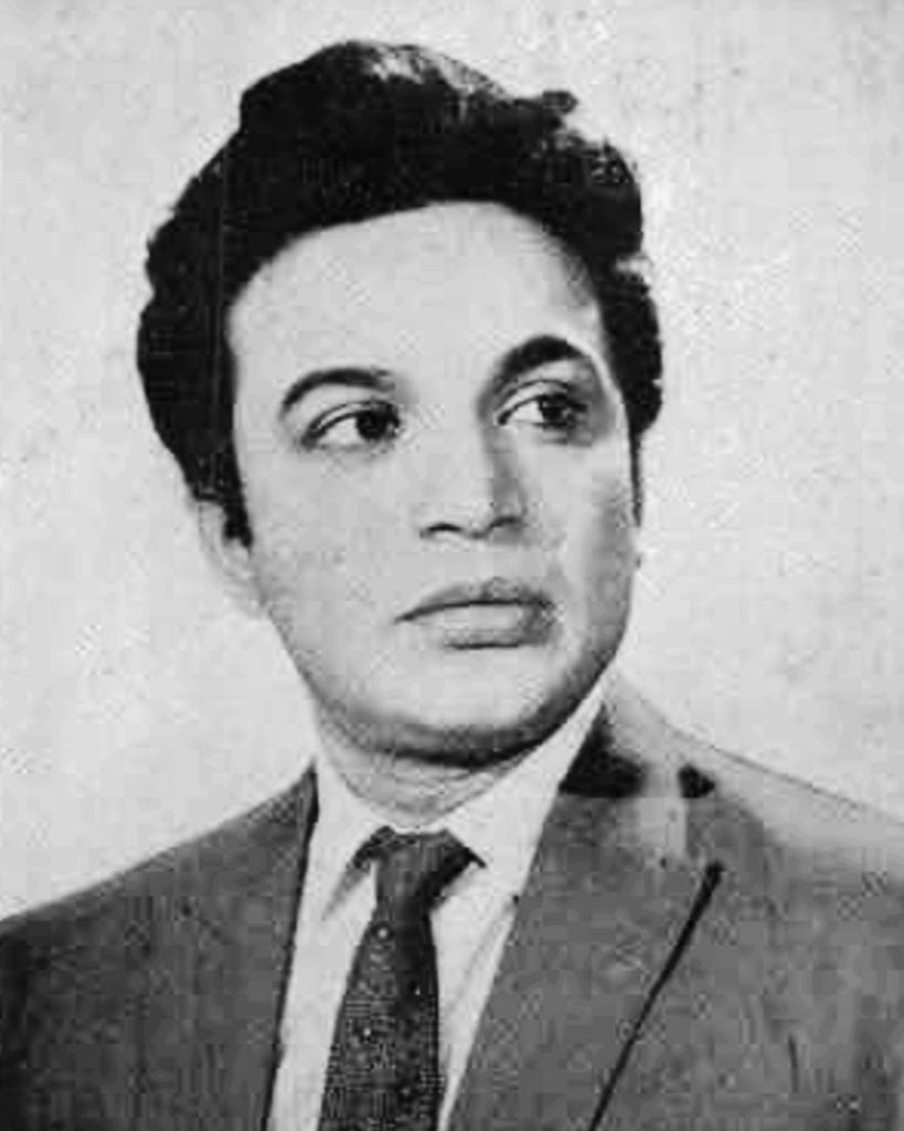 Black-and-white portrait of Uttam Kumar in a suit and tie, looking to one side