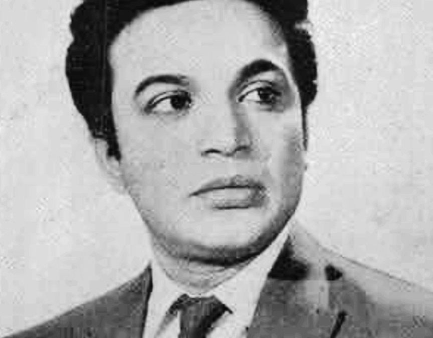 Black-and-white portrait of Uttam Kumar in a suit and tie, looking to one side