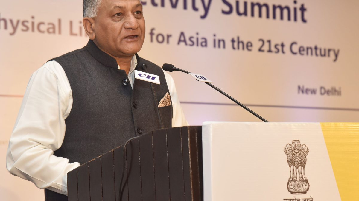 V. K. Singh in a dark waistcoat speaking at a Ministry of External Affairs lectern