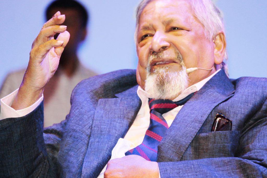 V. S. Naipaul seated, speaking into a microphone