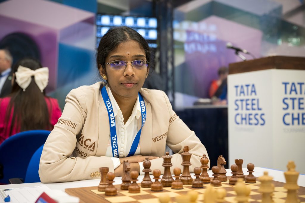 Vaishali Rameshbabu in a beige jacket seated at a chessboard at the Tata Steel tournament