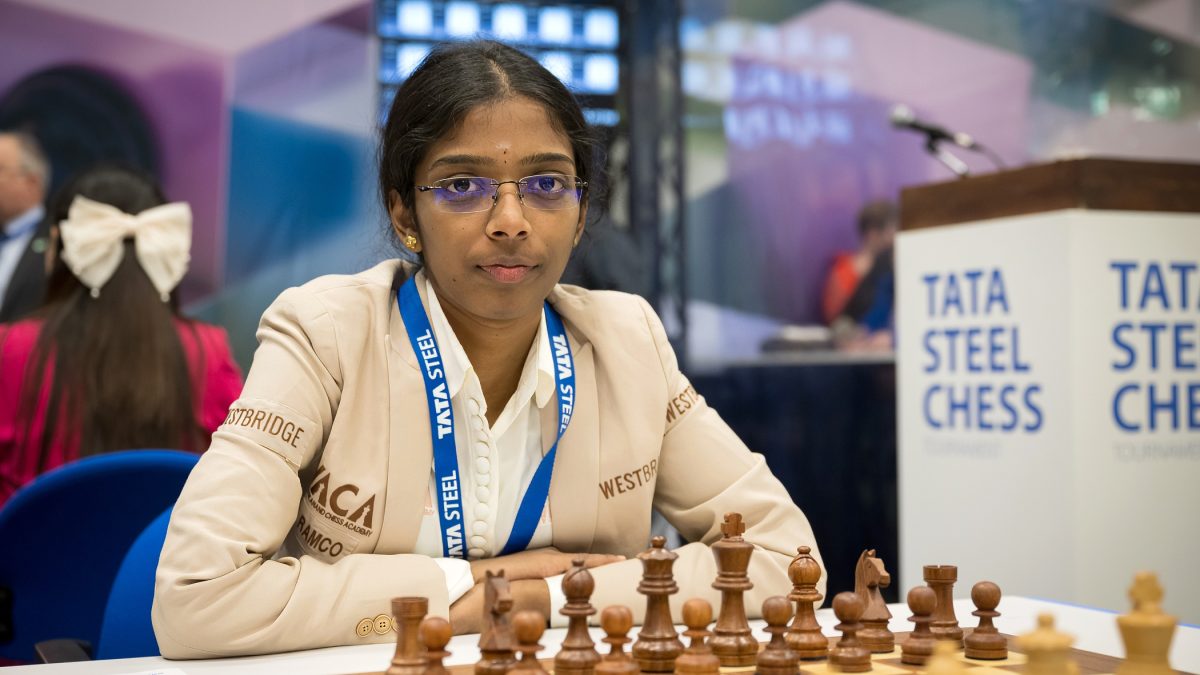 Vaishali Rameshbabu in a beige jacket seated at a chessboard at the Tata Steel tournament