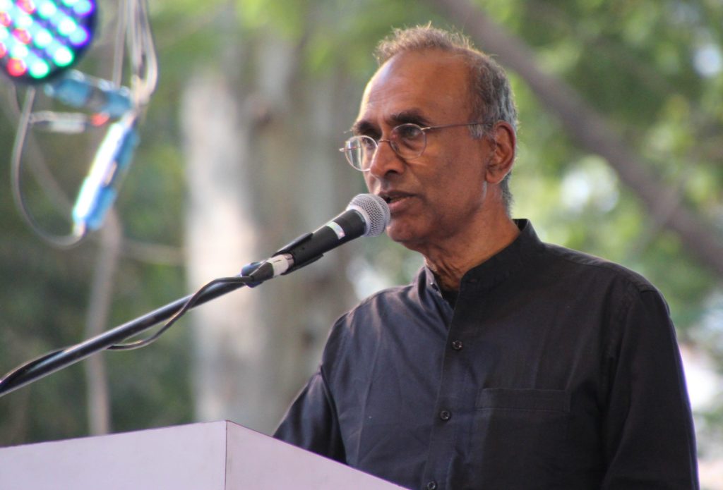 Venki Ramakrishnan in a dark kurta speaking at a microphone outdoors