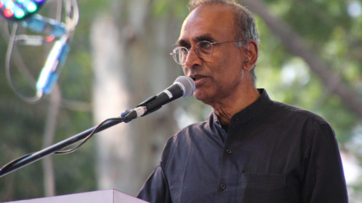 Venki Ramakrishnan in a dark kurta speaking at a microphone outdoors