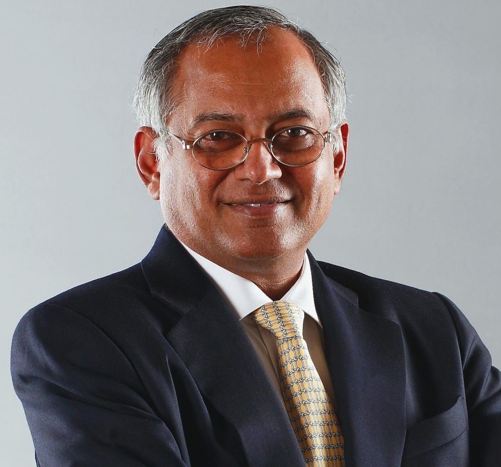 Venu Srinivasan in glasses, a dark suit and yellow tie