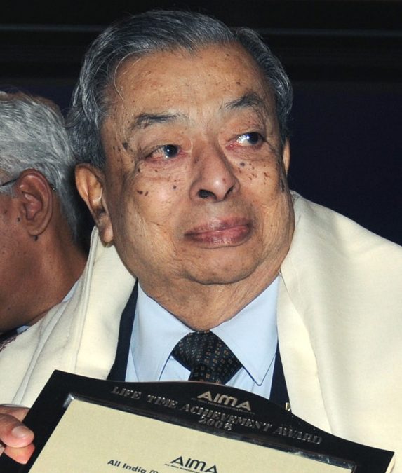An elderly Verghese Kurien in a suit and shawl holding a citation