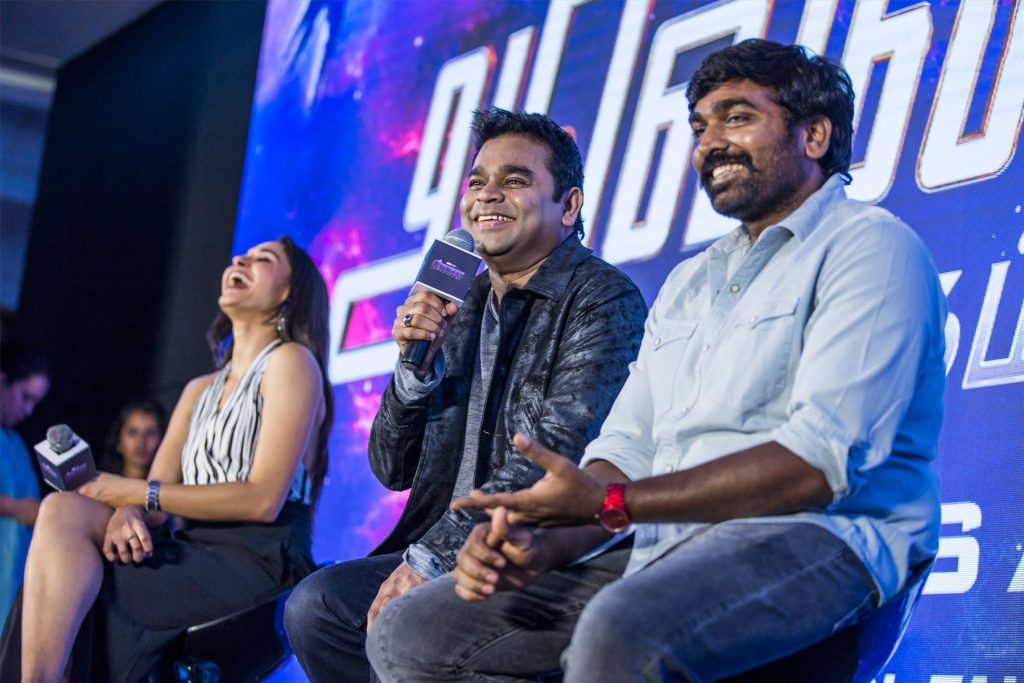 Vijay Sethupathi with a beard, in a blue shirt, smiling beside A. R. Rahman at a launch event