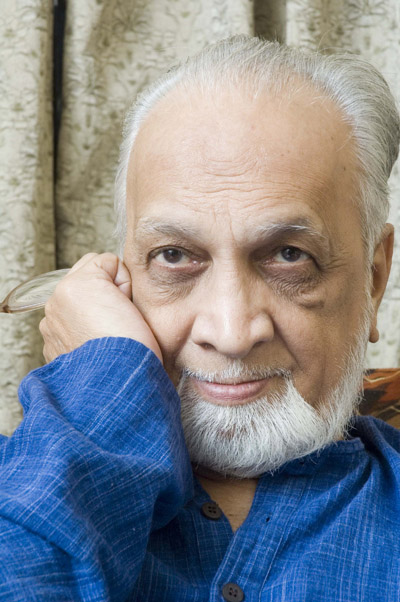 Vijay Tendulkar with white hair and beard, in a blue kurta, resting his head on his hand