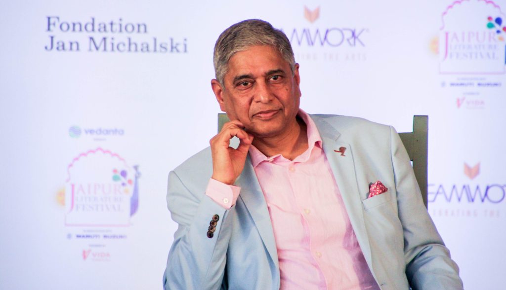 Vikas Swarup in glasses and a light blue jacket speaking into a microphone