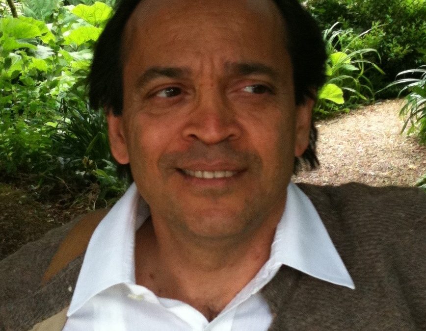 Vikram Seth smiling, in a jacket and open-necked shirt, in a garden