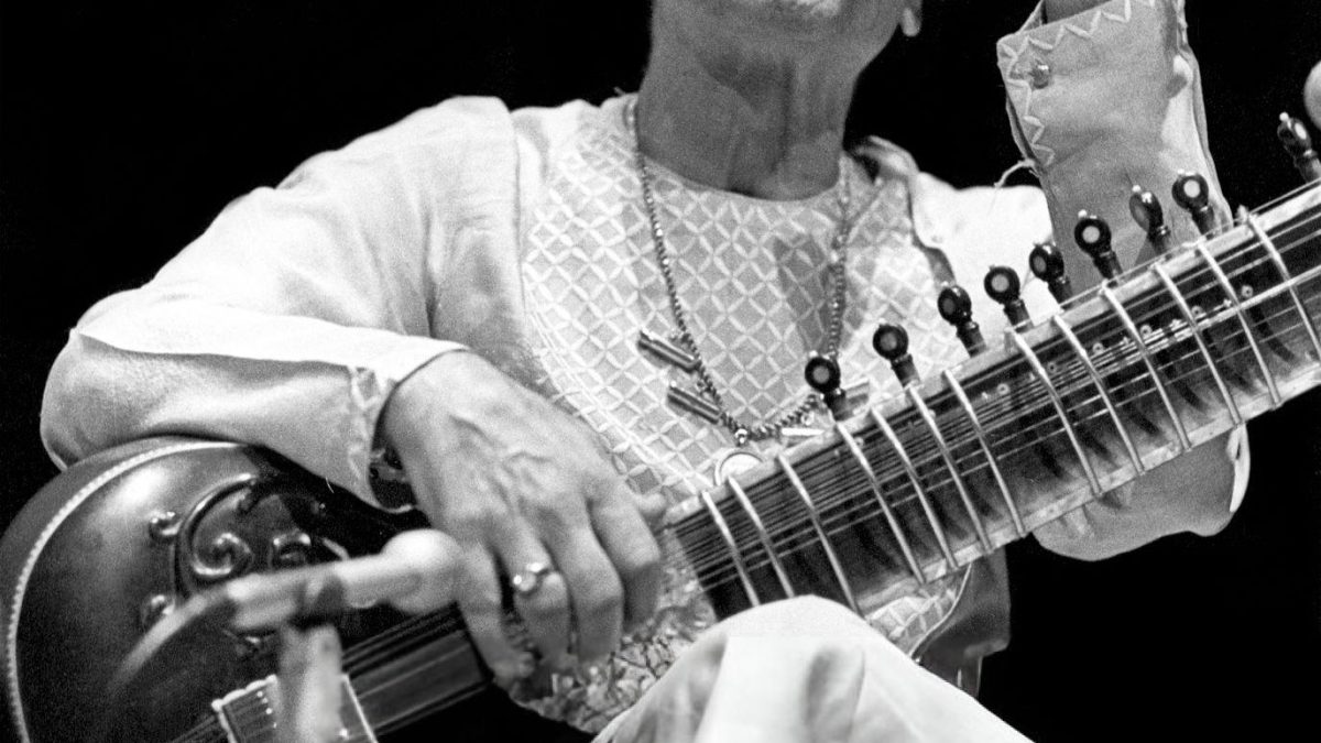 A black-and-white photograph of Vilayat Khan playing the sitar, one hand raised