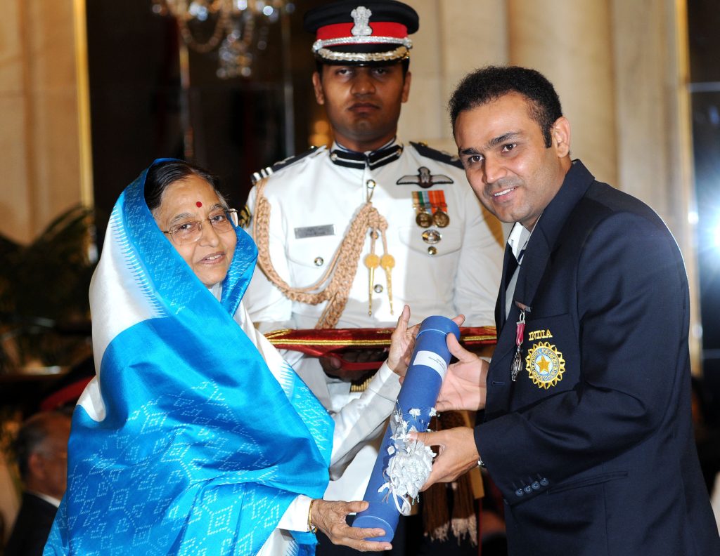 Virender Sehwag in a navy blazer receiving the Padma Shri from President Pratibha Patil