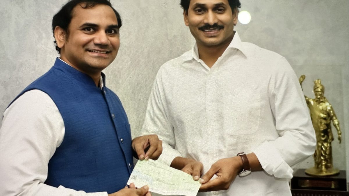 Y. S. Jagan Mohan Reddy in a white shirt smiling as he receives a cheque from a donor