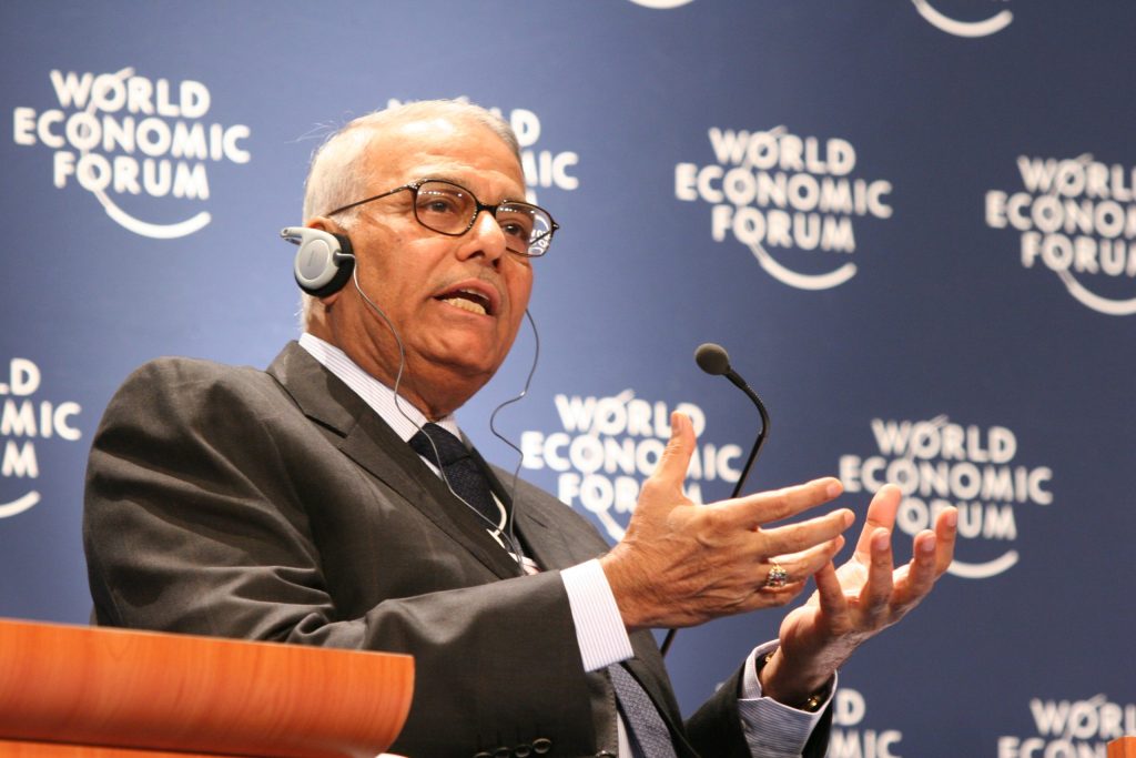 Yashwant Sinha wearing an interpreter's headset and gesturing with both hands as he speaks
