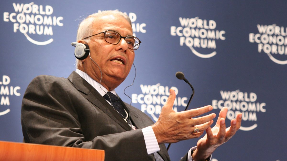Yashwant Sinha wearing an interpreter's headset and gesturing with both hands as he speaks