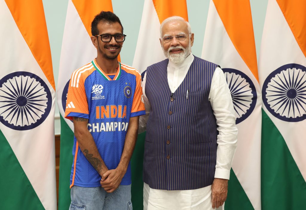 Yuzvendra Chahal in an India Champion jersey standing beside Prime Minister Narendra Modi in front of Indian flags