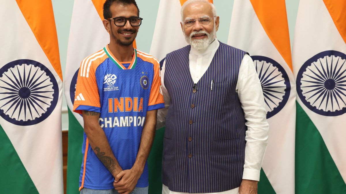 Yuzvendra Chahal in an India Champion jersey standing beside Prime Minister Narendra Modi in front of Indian flags
