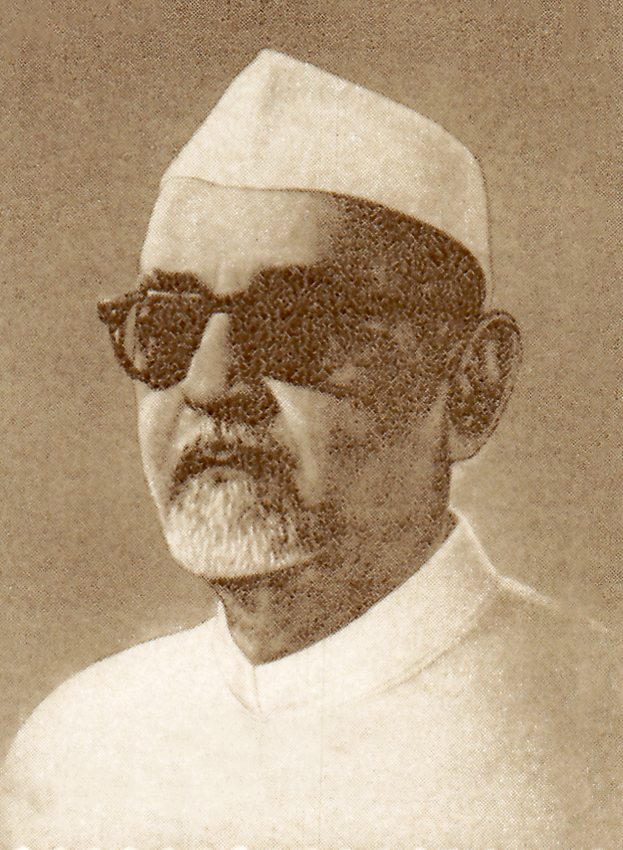 A portrait of Zakir Husain in a white cap and dark glasses, from a postage stamp