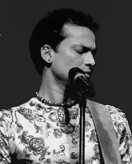 Zubeen Garg singing at a microphone in a patterned shirt